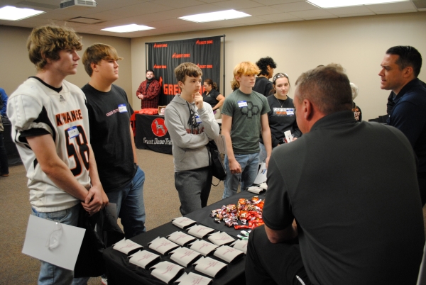 group of high school students at table talking to reps from manufacturing company