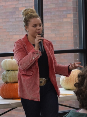 livestock judging team member with microphone and pumpkins on table in background