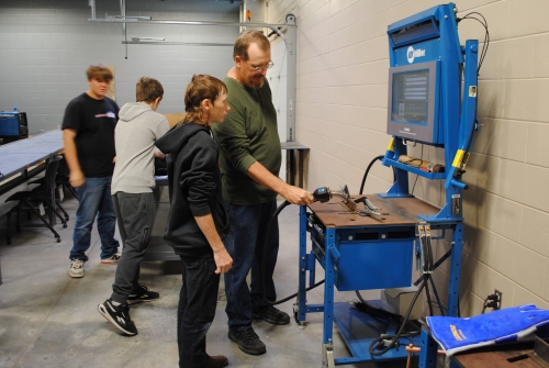 college instructor Paul Ericson showing high school student how to use welding simulator