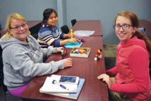 BHC graduate Kristie Amato sitting at table, playing legos with 2 young girls