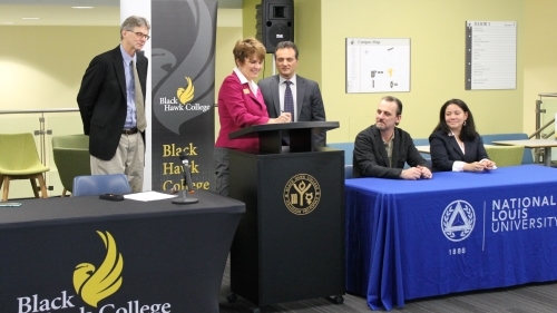 people at podium signing agreement