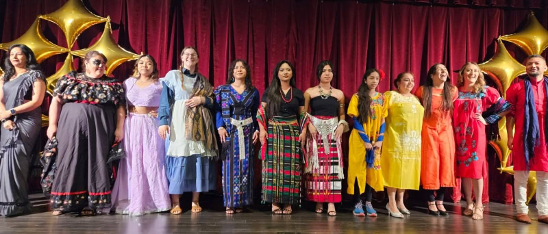 12 people on stage wearing their culture’s traditional clothing