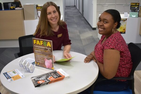 Financial Aid director and student sitting at a table smiling