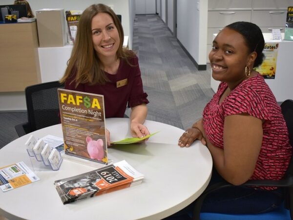 Financial Aid director and student sitting at a table smiling