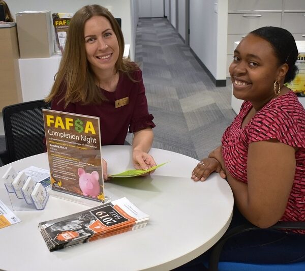 Financial Aid director and student sitting at a table smiling