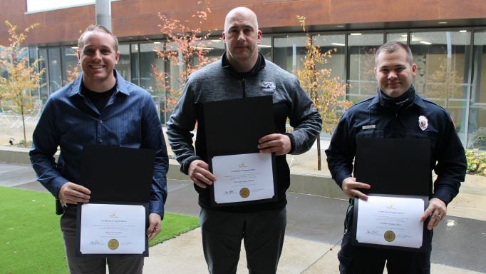 3 people holding certificates of appreciation