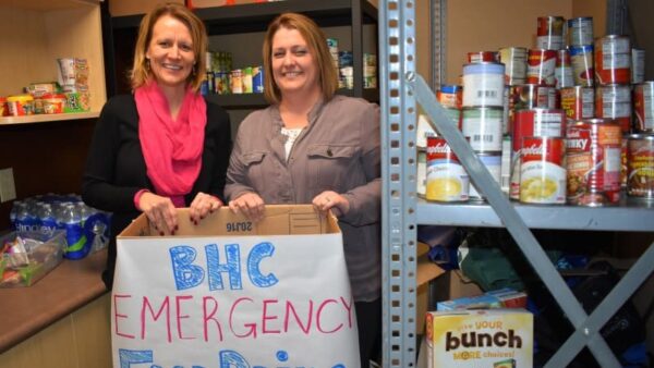 BHC staff members hold a food drive donation box in the pantry