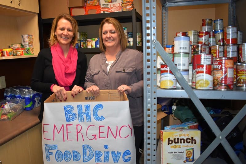 BHC staff members hold a food drive donation box in the pantry