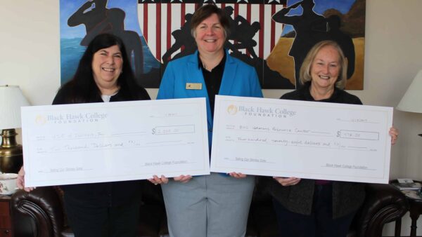 three women holding two oversized checks