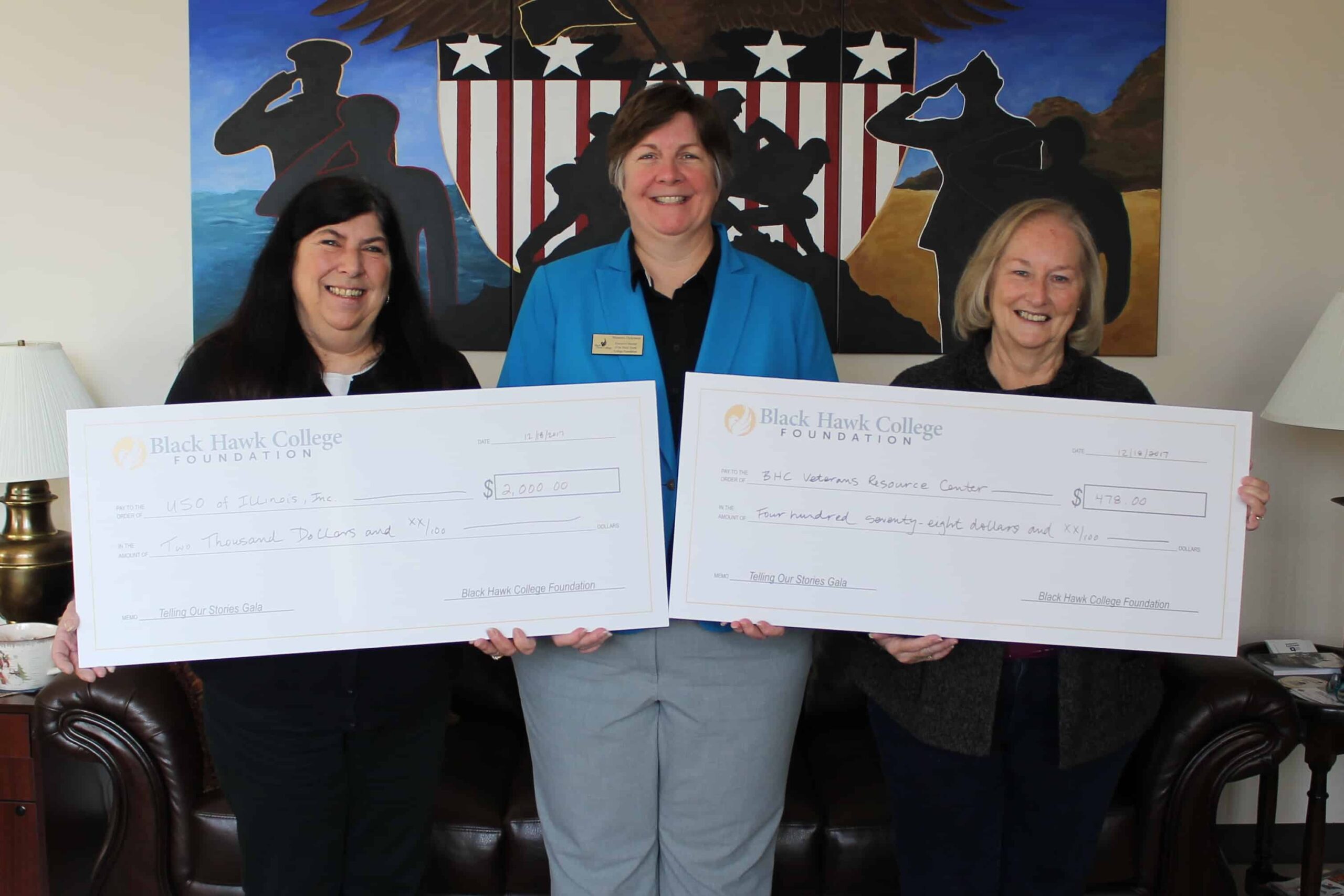 three women holding two oversized checks