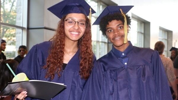 2 grads in caps & gowns smiling at camera