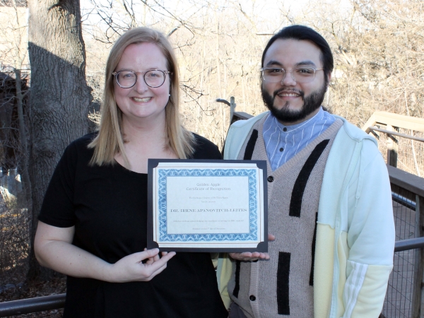 Irene Leites holding award certificate standing outdoors with Victor Cardoza