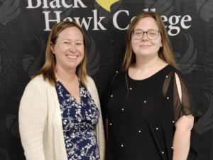 2 people standing in front of Black Hawk College banner