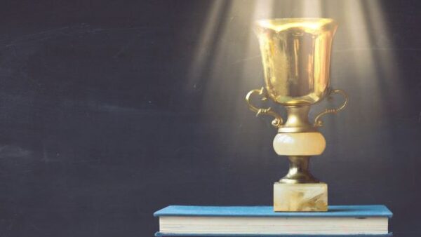 golden trophy on pile of books in front of blackboard