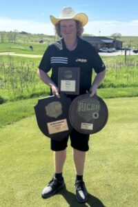 golfer on golf course holding two award plaques