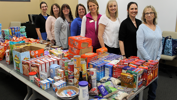 women standing behind a table filled with food pantry items