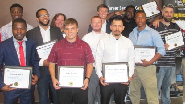 12 men & 1 woman standing & holding certificates