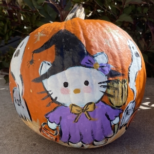 Hello Kitty dressed as a witch and ghosts painted on a pumpkin