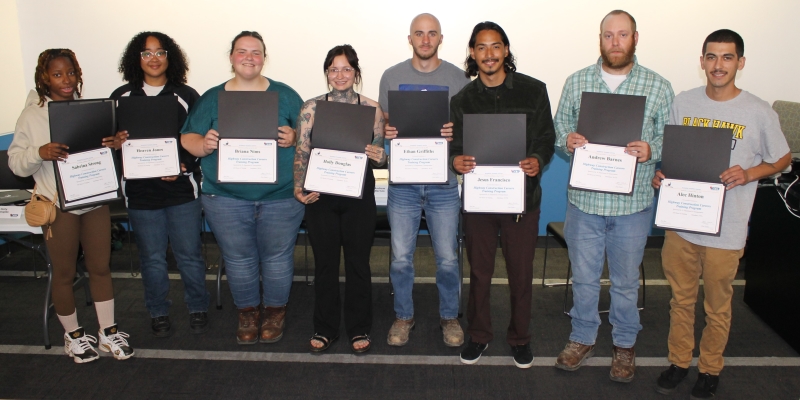 8 people standing in line facing camera and holding certificates