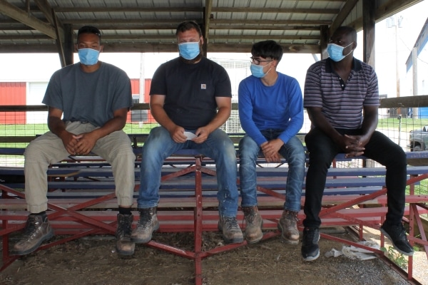 4 people sitting on bleachers wearing masks