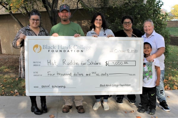 6 people standing outdoors with oversized check