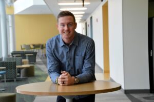 Ian Hutto leaning on table in blue shirt