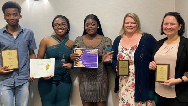 5 people smiling at camera and holding awards