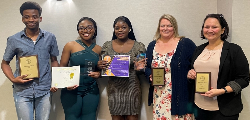 5 people smiling at camera and holding awards