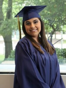 Optional Education grad Monica Hurtado in cap & gown smiling at camera