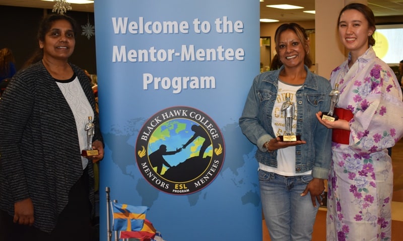 3 women standing by banner holding awards