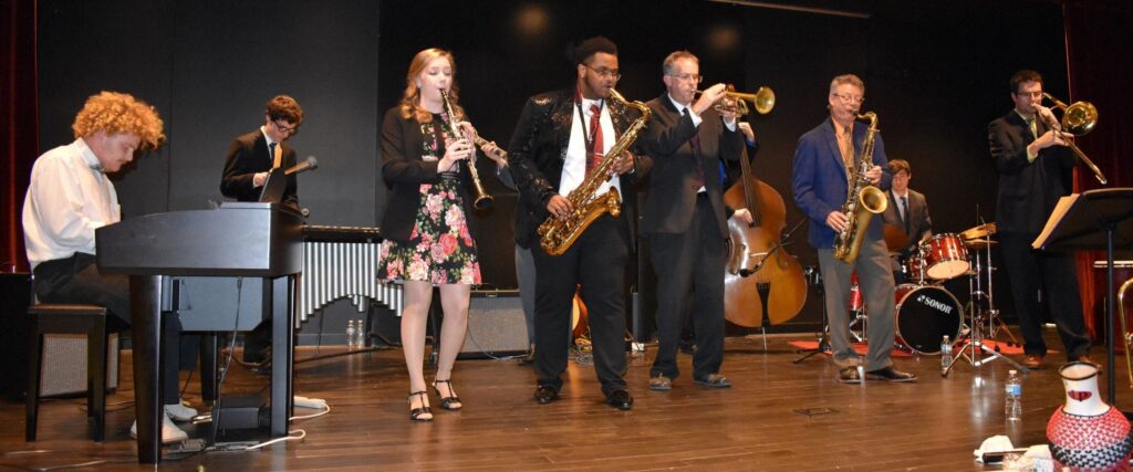 8 jazz musicians on stage playing various instruments