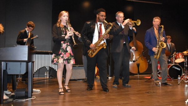 8 jazz musicians on stage playing various instruments