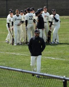 baseball coach in foreground, team in background on field