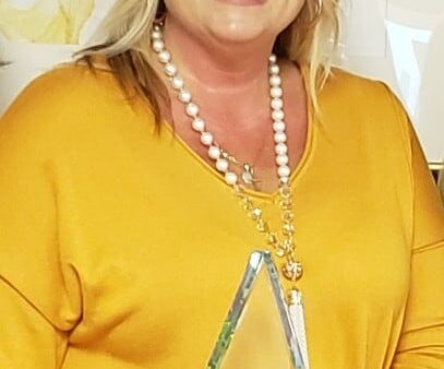 smiling woman in yellow shirt holding triangular acrylic award