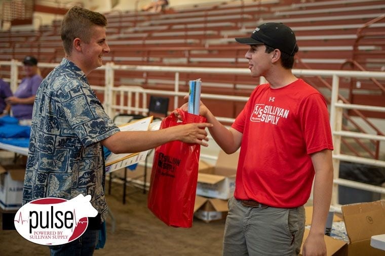 BHC graduate handing bag of supplies from sullivan supply to man