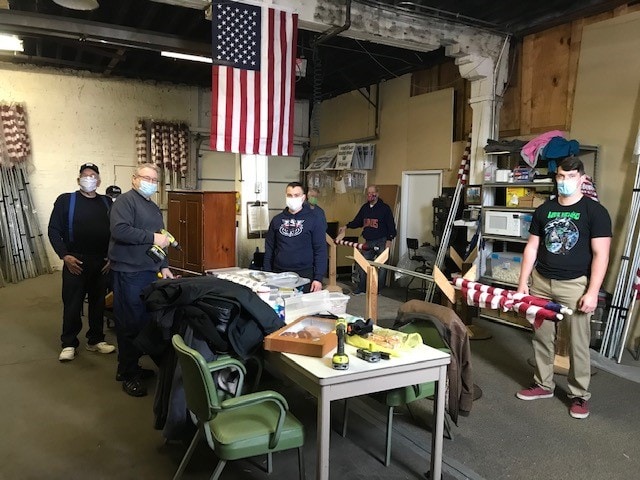 a group of masked men around a table with power tools and flags