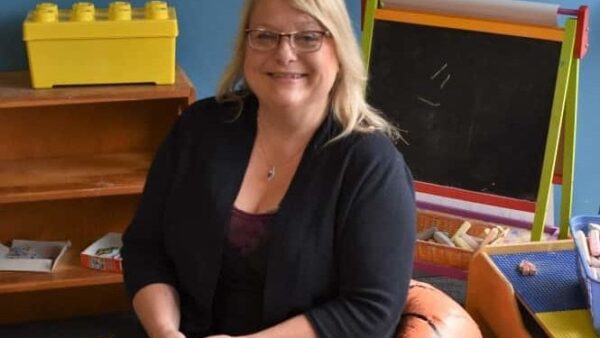 BHC graduate sitting in a child's waiting area on a beanbag chair