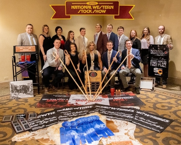 16 people standing with variety of awards