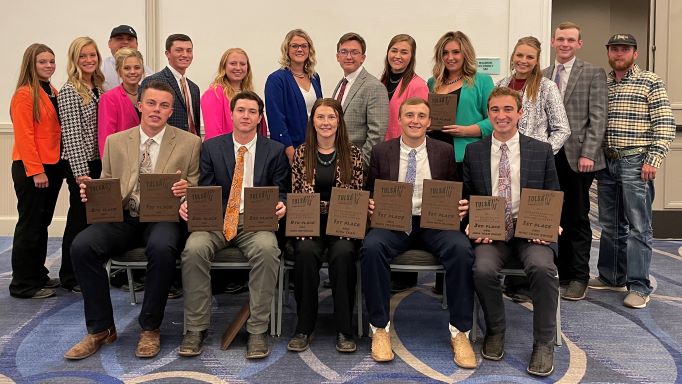 5 people seated with awards and 13 people standing