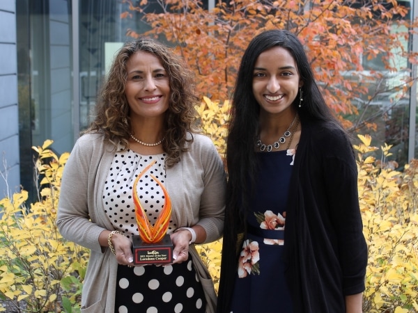 Loredana Cooper holding award with Saheli Sheth standing outdoors on fall day