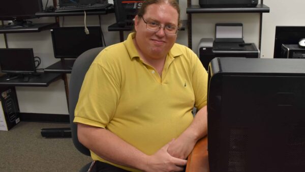 man sitting at desk with computer tower