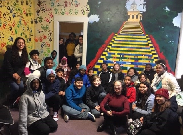 nonprofit co-founder sits on the floor surrounded by students