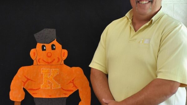 Kewanee High School teacher standing in front of a quilt featuring the school's mascot, a boilermaker