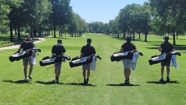 5 golfers with bags walking on the golf course