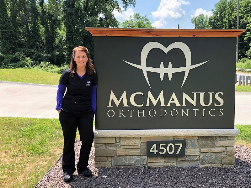 woman standing next to McManus Orthodontics sign