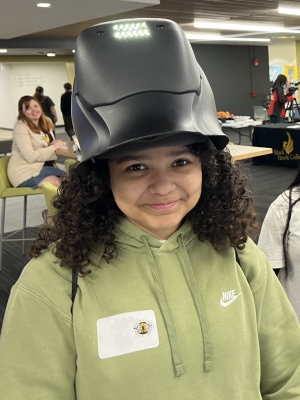 Middle school student with welding hood on her head