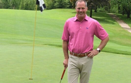 coach posing on golf course