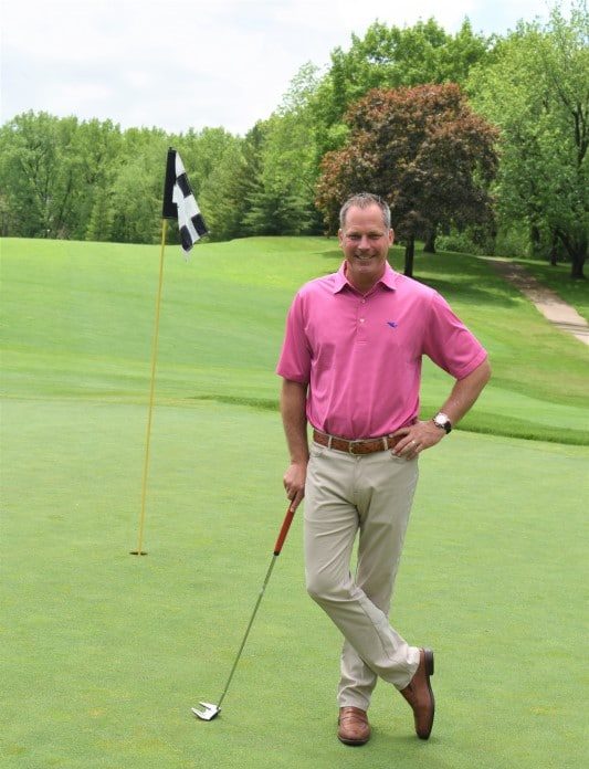 BHC alumnus Mike Downing standing in golf course, next to a flag