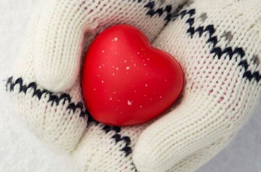 hands in white mittens holding red heart