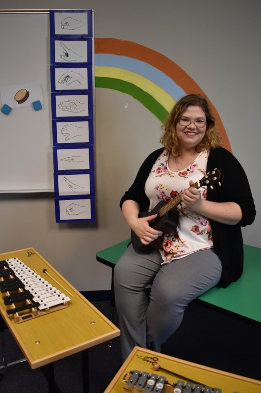 woman holding ukulele in a music room